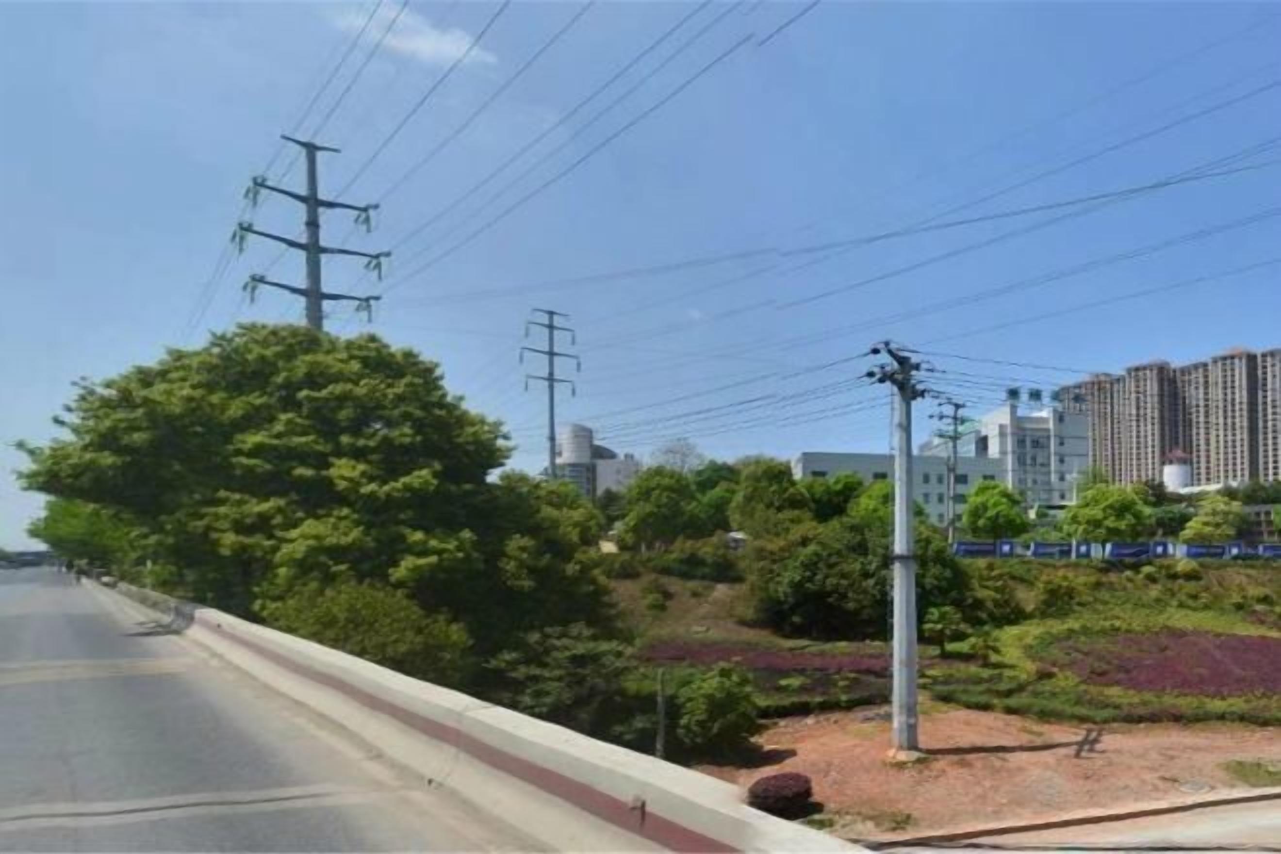 A road with a sidewalk, power lines, and buildings in the background.