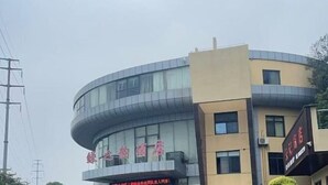 A hotel with a curved facade, large windows, and a sign with red lettering. - Lvzhiyun International Hotel (Liuyang)