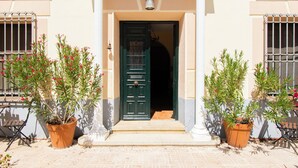 A building entrance with a green door, potted plants, and a white railing.