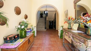 A hotel lobby with a staircase, a reception desk, and a large mirror.