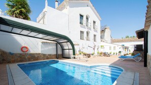 A swimming pool with a curved edge, a lifebuoy, and a stone wall.