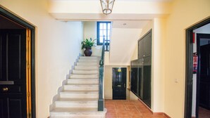 A staircase with a potted plant, a black door, and a tiled floor.