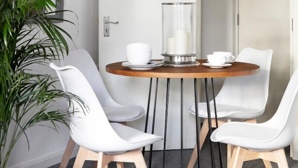 A modern dining area with a round table, white chairs, and a potted plant. - Watford WD18 - Beautiful 1Bedroom/1Bathroom Flat with Free Parking & Free WIFI (Watford)