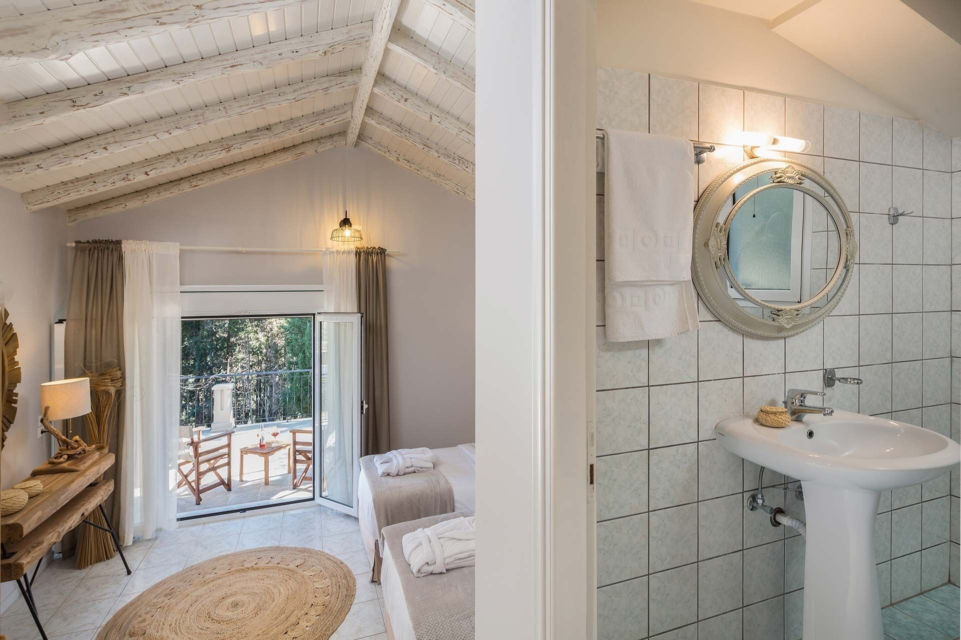 A hotel room with a balcony, a round mirror, a white sink, and a bed with a view of the outdoors.