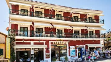 A two-story hotel with balconies, outdoor seating, and a visible storefront.