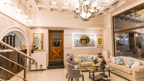 A spacious living room with a chandelier, a sofa set, a coffee table, and a large window. - Paradise Hotel (Parga)