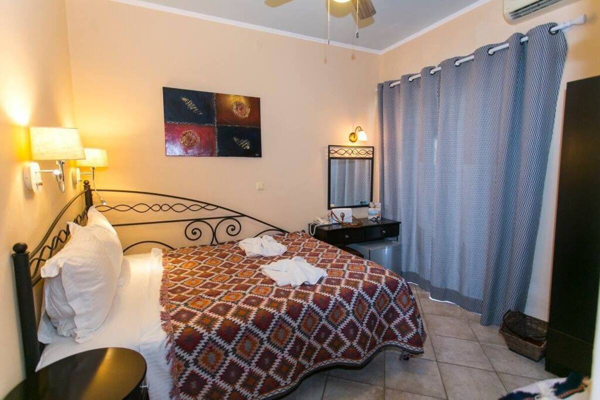 A neatly made bed with a patterned bedspread, a bedside lamp, and a wall-mounted artwork.