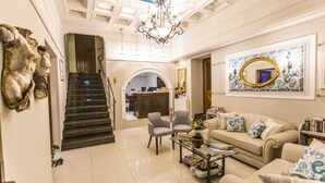 A spacious living area with a staircase, a chandelier, a sofa set, and a coffee table. - Paradise Hotel (Parga)