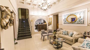 A spacious living area with a staircase, a chandelier, a sofa set, and a coffee table.