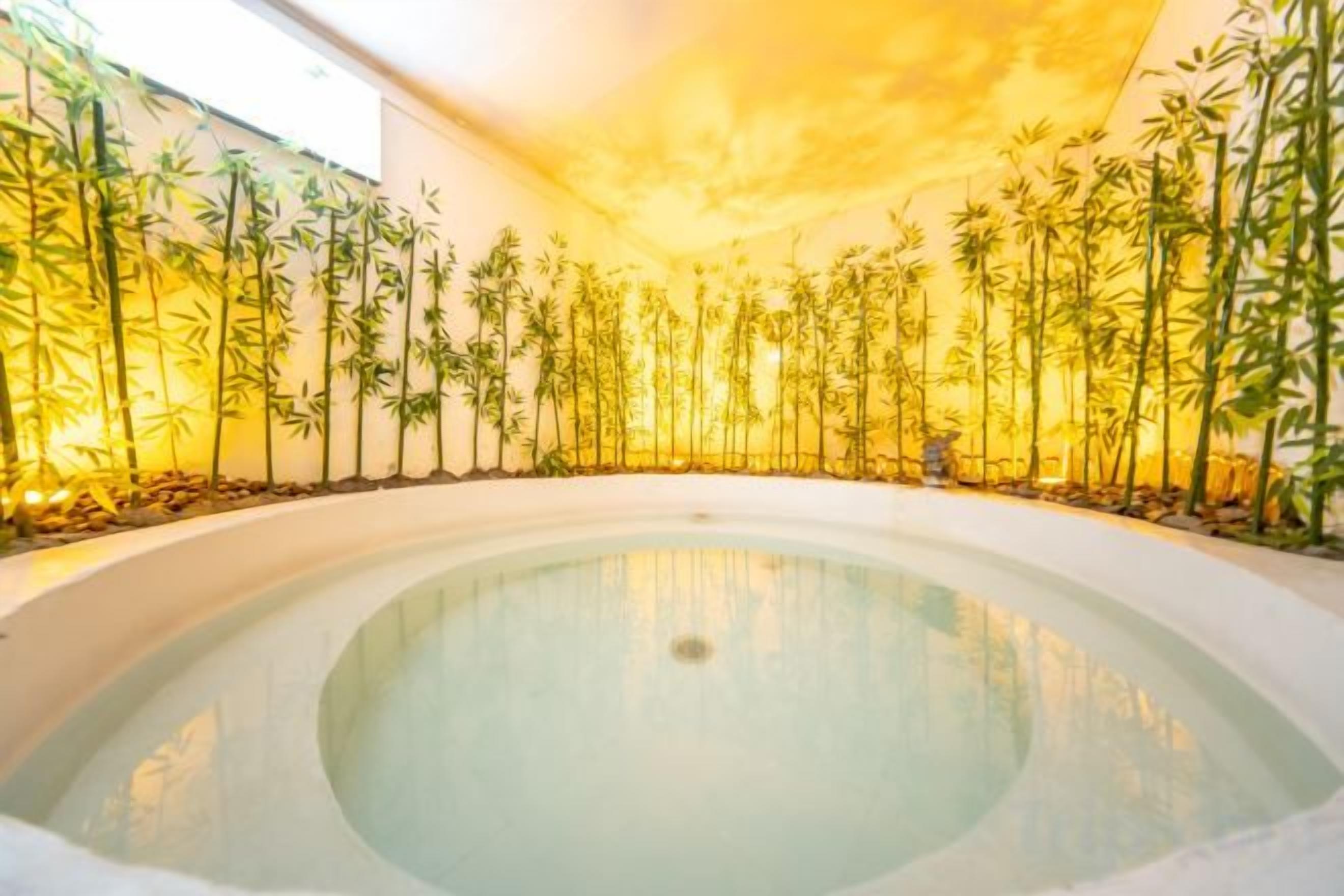 Un bain à remous entouré de plantes de bambou, dans un décor intérieur moderne.