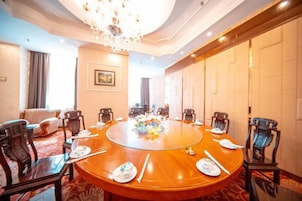 A conference room with a round table, chairs, and a chandelier.
