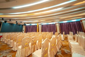 A conference room with rows of chairs, a stage, and a large screen. - Kailong Hot Spring Hotel (CHENZHOU)