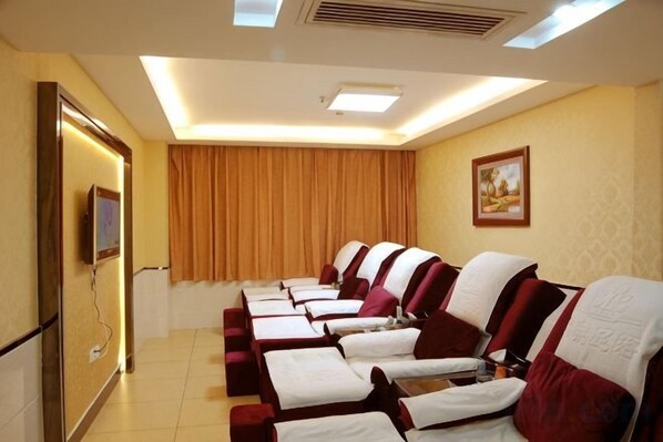 A room with multiple massage therapy beds arranged in a row, a television on the left, and a painting on the wall.