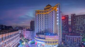 A multi-story hotel with a prominent corner location, featuring a large balcony and a rooftop terrace.