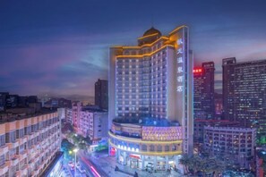 Un hotel su più piani con una posizione d'angolo ben visibile, dotato di un ampio balcone e una terrazza panoramica.