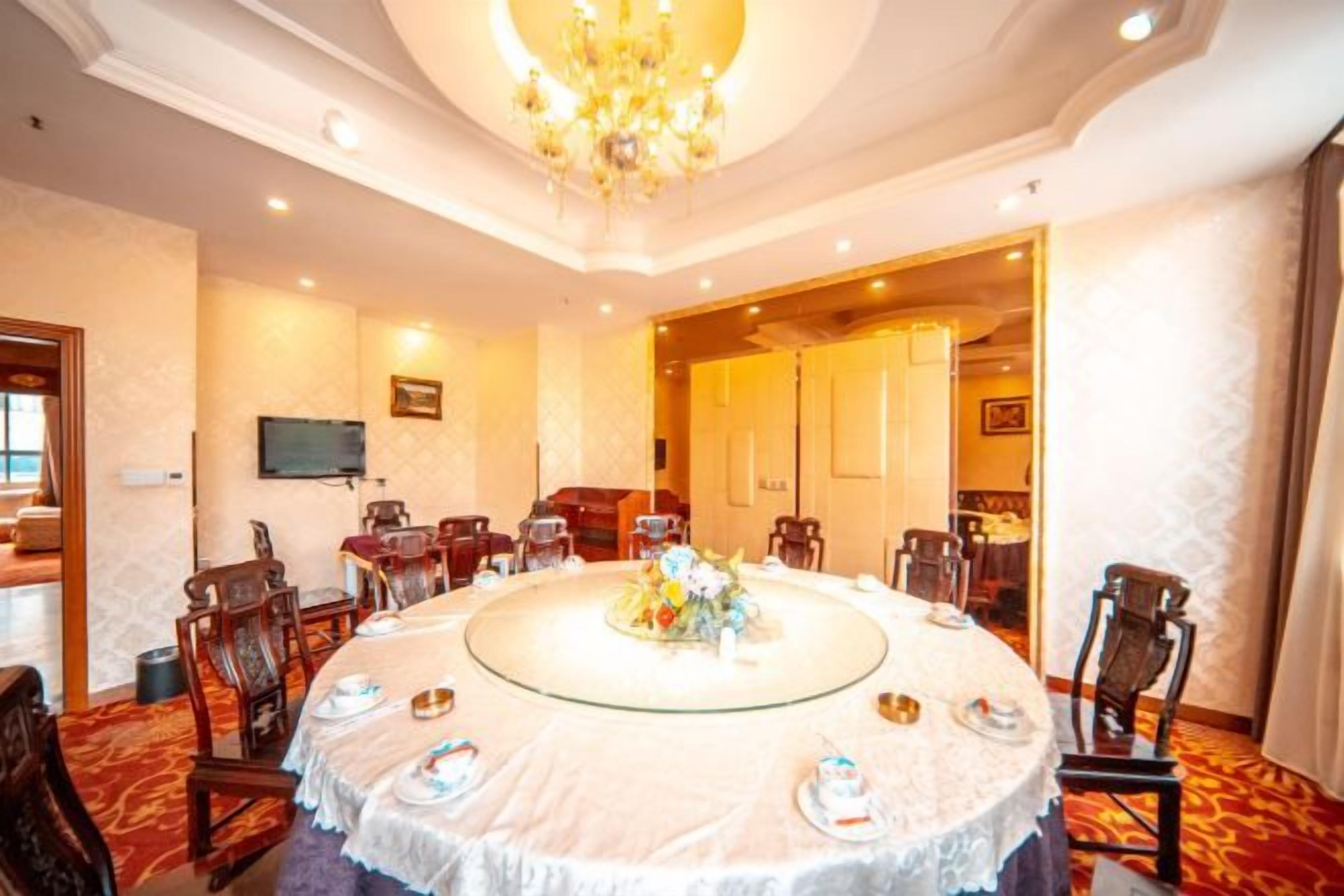 A conference room with a round table, chairs, and a chandelier.