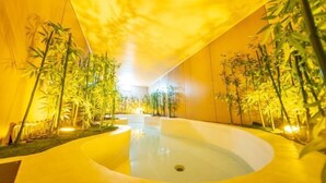 A modern indoor pool area with a central water feature, surrounded by bamboo plants and illuminated by warm lighting. - Kailong Hot Spring Hotel (CHENZHOU)
