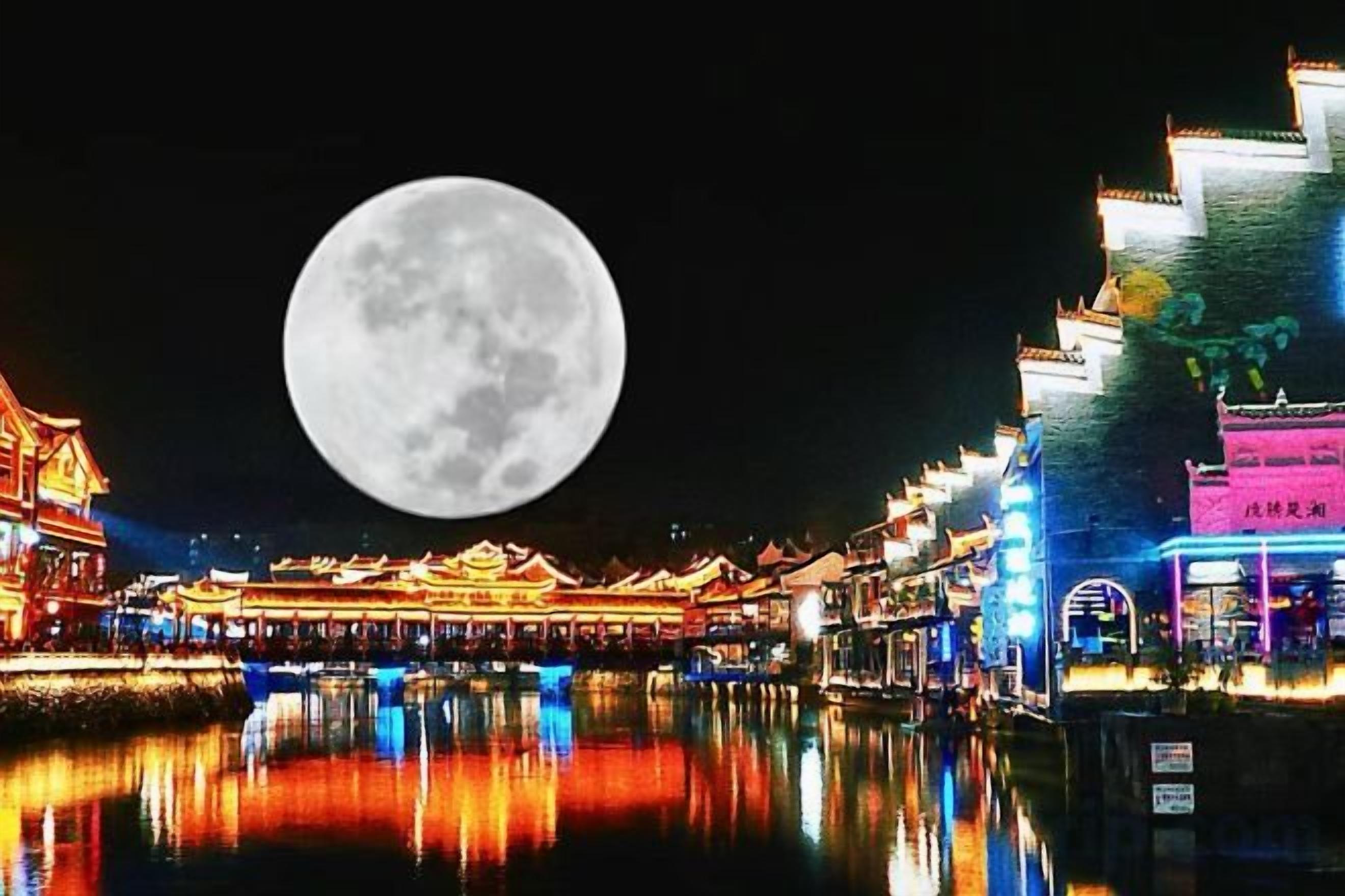 Un bâtiment traditionnel qui se reflète dans l’eau, une pleine lune dans le ciel et une enseigne avec des caractères chinois.