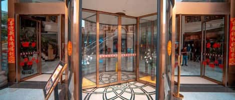 A hotel entrance with a revolving door, glass doors, and a tiled floor.