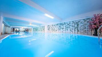 An indoor swimming pool with clear blue water, surrounded by walls with a floral pattern.