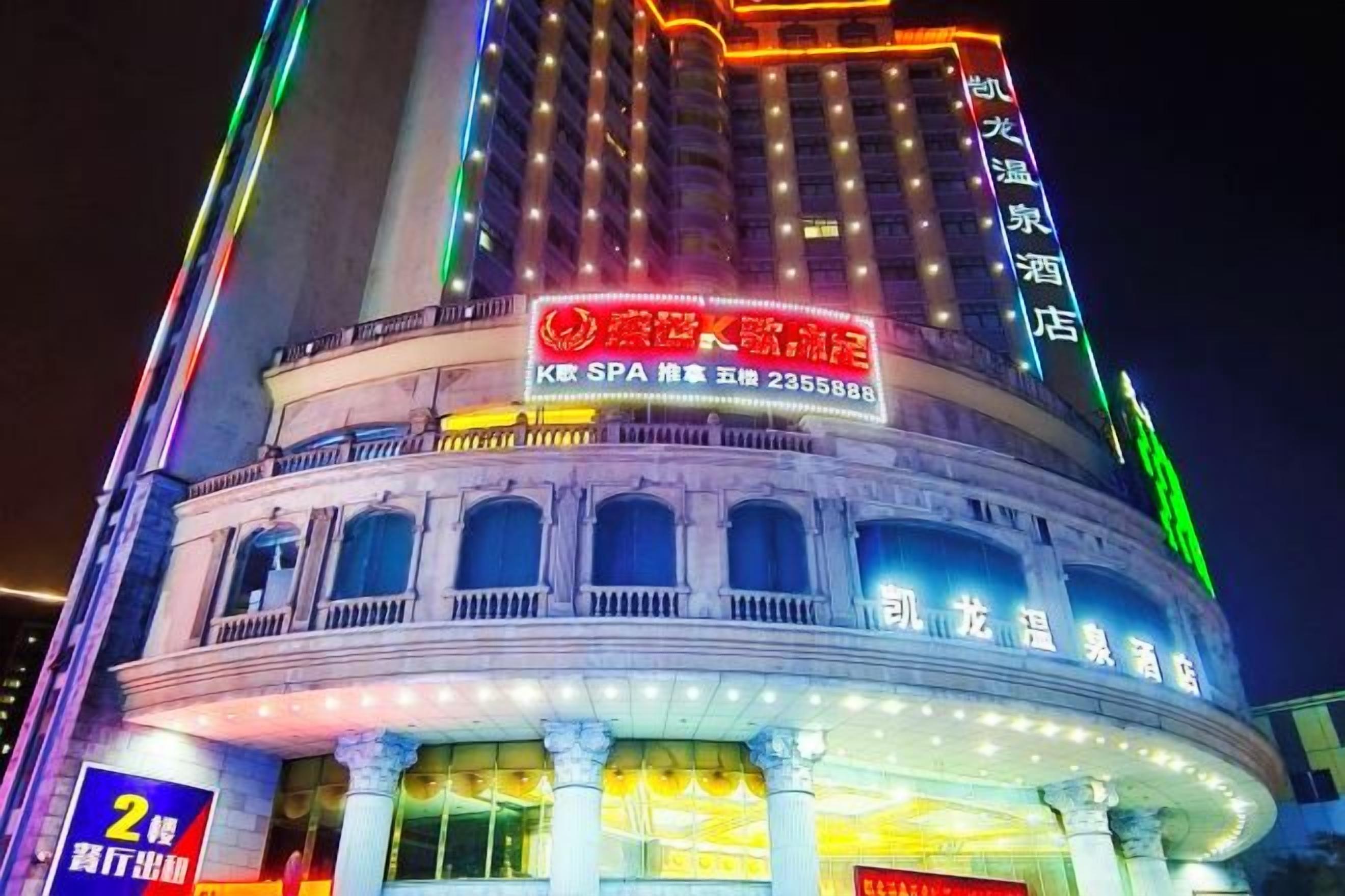 A multi-story building with illuminated signage, including a prominent red sign with white text and a green neon sign on the top.