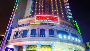 A multi-story building with illuminated signage, including a prominent red sign with white text and a green neon sign on the top.