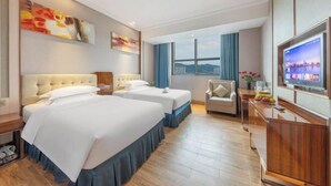 A hotel room with two beds, a TV, a desk, and a window with a city view. - Kailong Hot Spring Hotel (CHENZHOU)