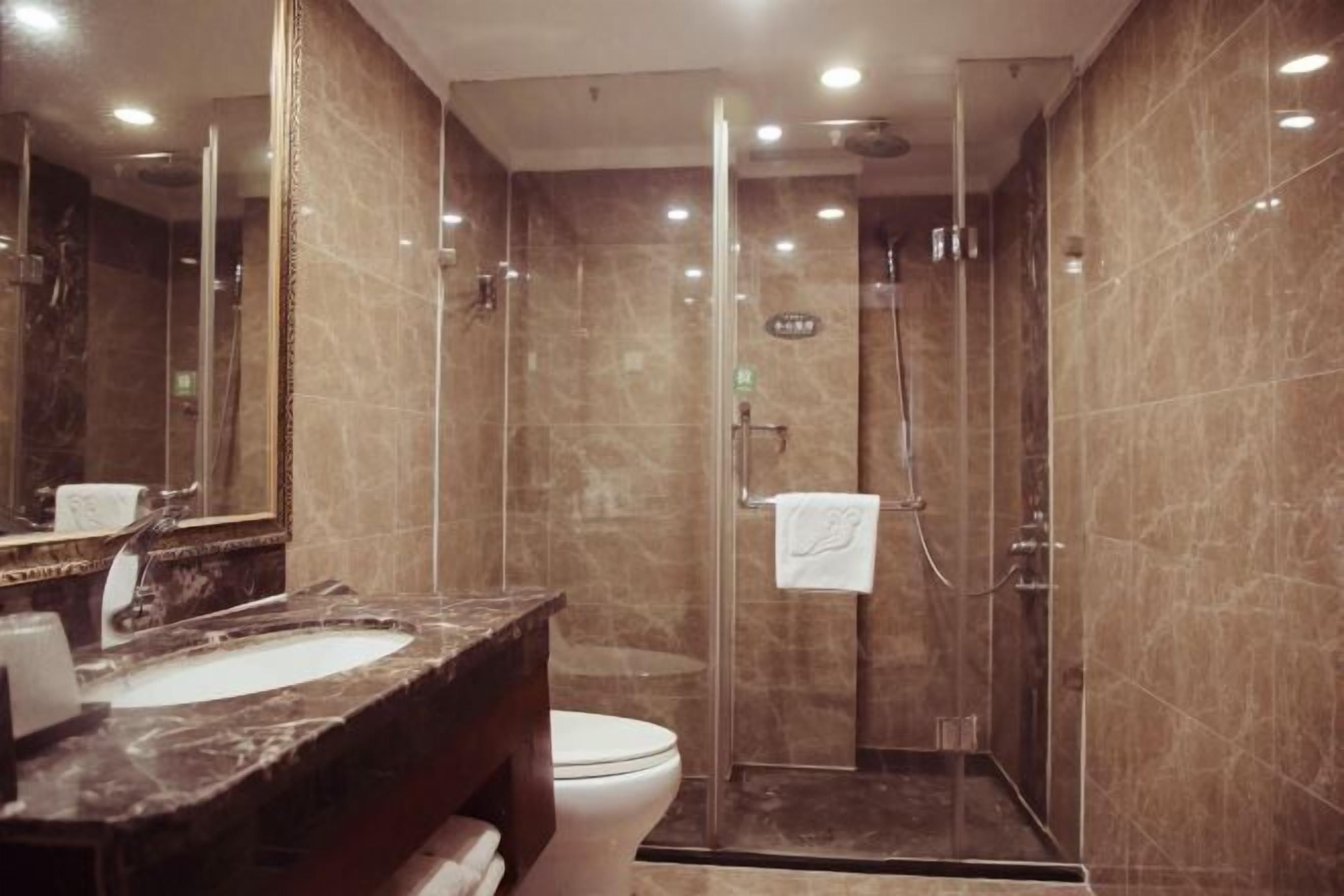 A modern bathroom with a marble sink, a toilet, and a glass-enclosed shower area.