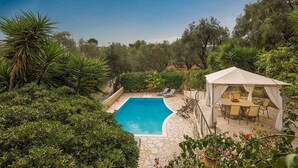Une piscine entourée d’une végétation luxuriante, agrémentée d’un belvédère et d’un espace salon extérieur.