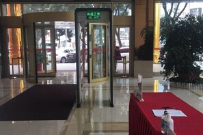 A hotel entrance with a revolving door, a reception desk, and a red carpet. - Huatian Hotel (Xiangtan)