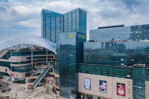 Un edificio moderno urbano con fachada de vidrio, un pasillo cubierto para peatones y una escalera visible.