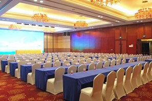 A conference room with rows of tables and chairs, a large screen, and a stage. - Huatian Hotel (Xiangtan)