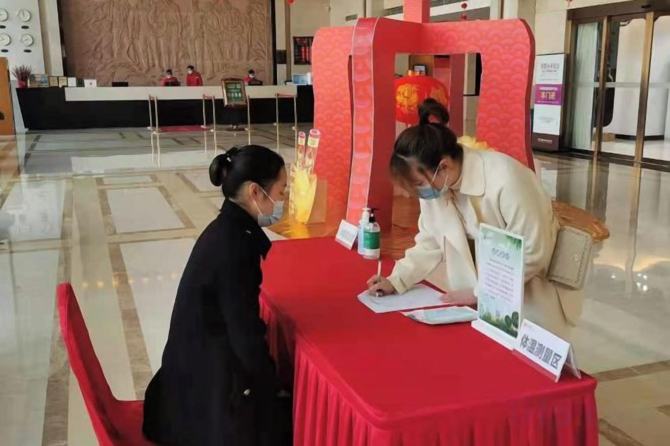 A reception desk with a red tablecloth, a sign with text, and a decorative item with lights.