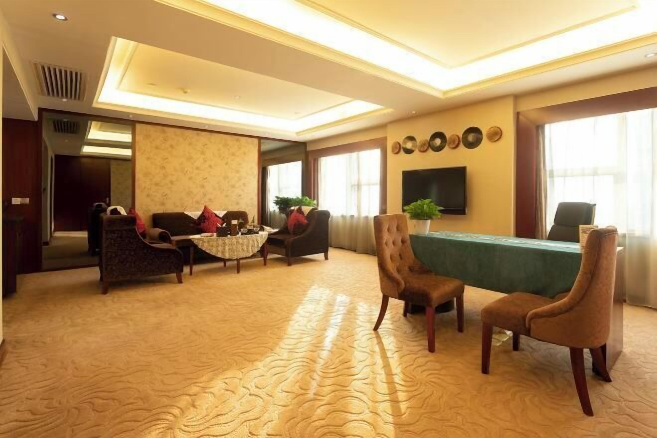 A spacious room with a large table, several chairs, a sofa, and a television.