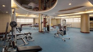 Et fitnesscenter med forskellig træningsudstyr, store vinduer og et højt til loftet.