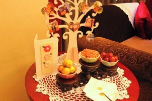 Una mesa con un centro de mesa decorativo con un árbol, cuencos de fruta y un mantel blanco sobre un posavasos.