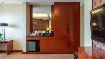 A compact hotel room with a kitchenette, a flat-screen TV, and a wardrobe.