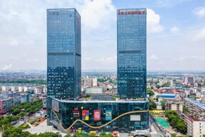 Two high-rise buildings with a curved glass facade, surrounded by a cityscape. - Huatian Hotel (Xiangtan)