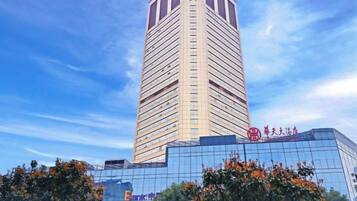 Um edifício alto e moderno com fachada de vidro e um letreiro vermelho grande no topo.