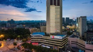 A high-rise building with a modern design, featuring a prominent vertical structure and illuminated windows.