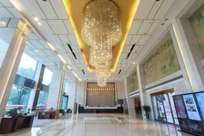 A spacious lobby with a large chandelier, a reception desk, and a digital information board. - Huatian Hotel (Xiangtan)