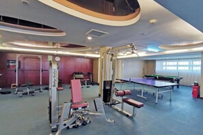 Un gimnasio con equipamiento de ejercicio, una mesa de ping pong y una mesa de billar.