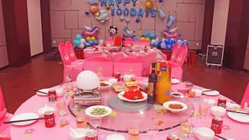 A round table with pink tablecloth, balloons, and party decorations.
