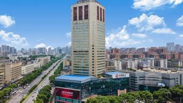 A high-rise building with a modern design, surrounded by a cityscape with other buildings and a clear sky.