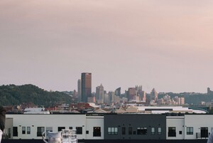 Un horizonte urbano con varios edificios, incluyendo un alto edificio destacado que muestra la palabra 'LYNCH'.
