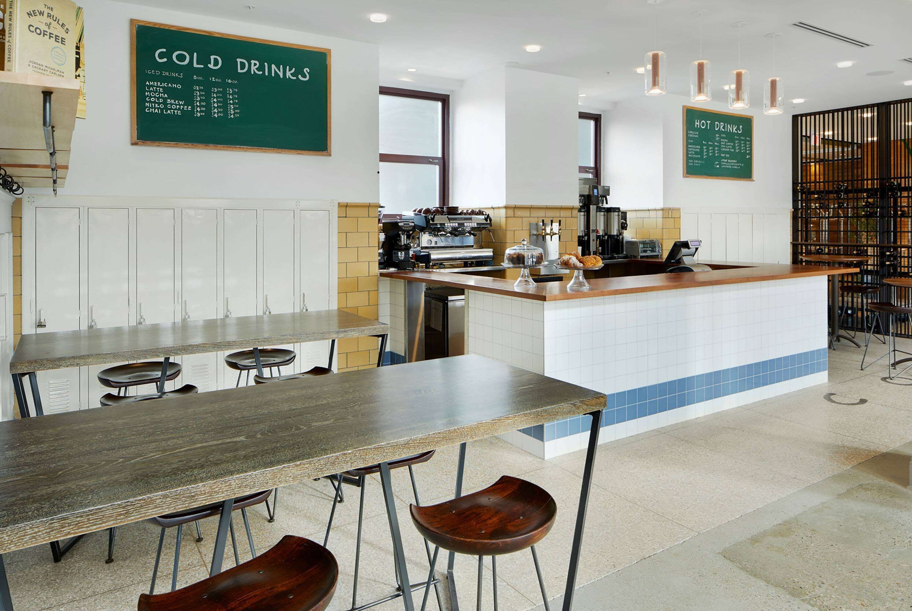 Ein modernes Café mit einer langen Theke, Hockstühlen und einer Tafel für kalte und heiße Getränke.