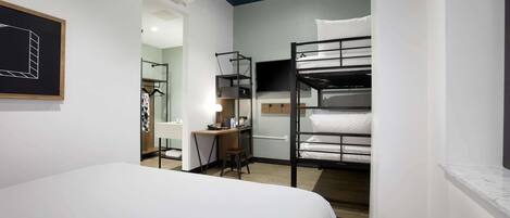 Una habitación de hotel moderna con literas, un escritorio con silla, un espejo y un cuadro en la pared.