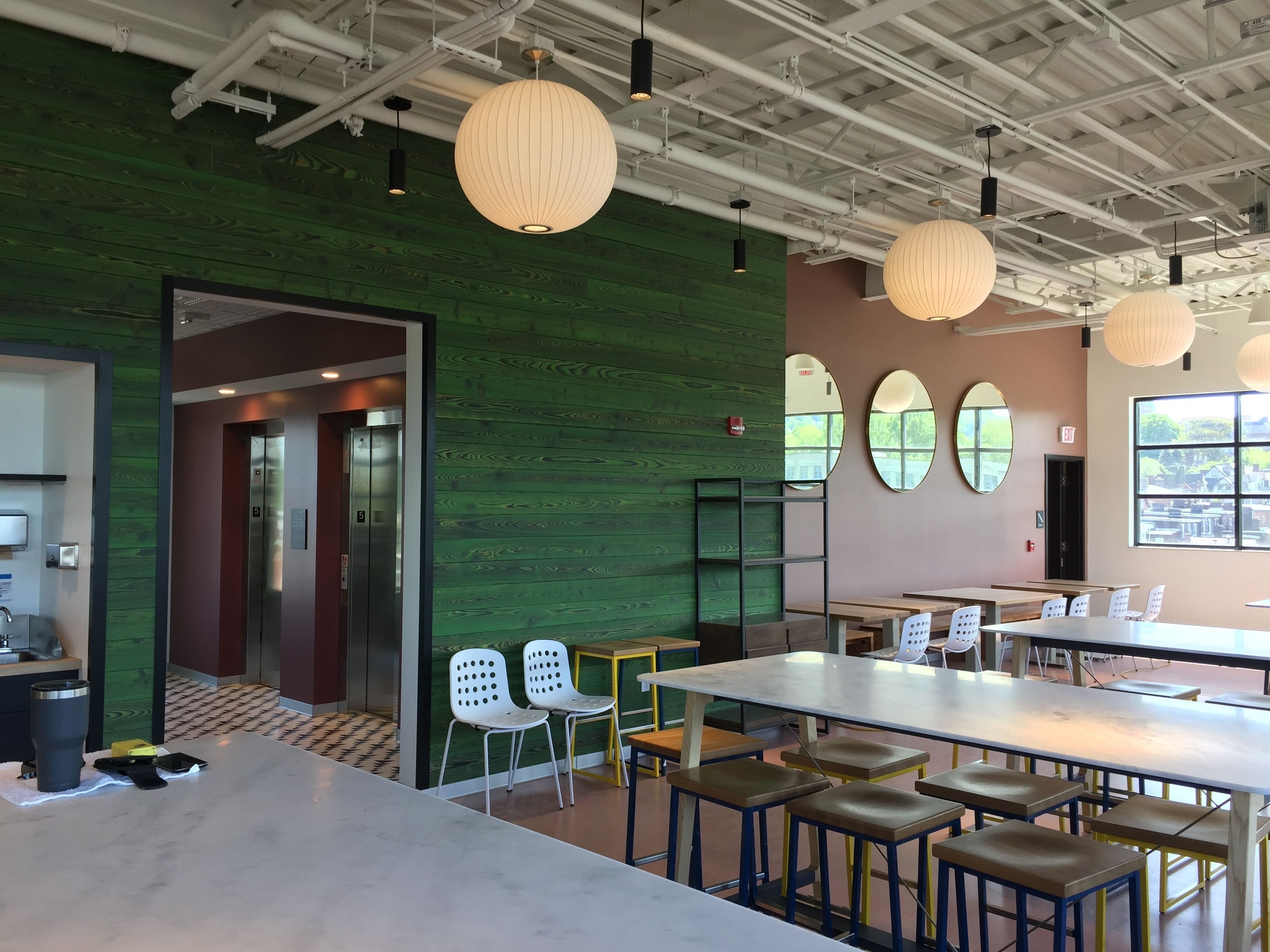 A modern interior with a green wall, white and brown chairs, and tables.