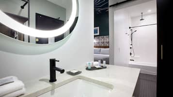 A modern bathroom with a large mirror, a sink, and a shower.