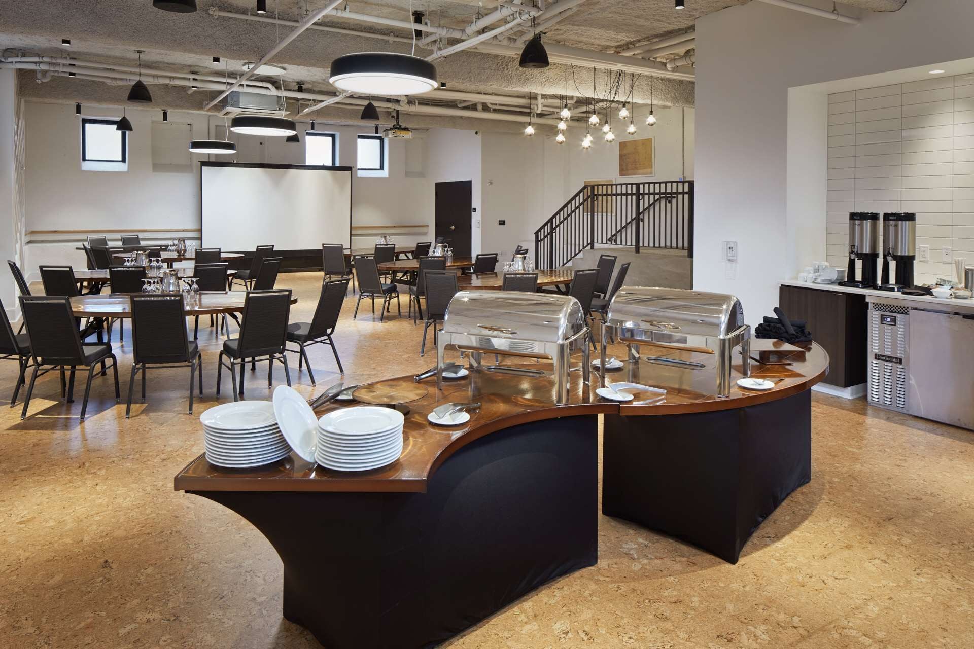 A modern kitchen area with a buffet setup, including a counter with a grill, plates, and cutlery.